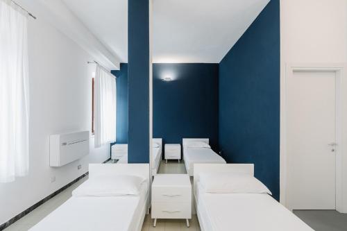 una camera con letti bianchi e una parete blu di OSTELLO HENRY a Buggerru