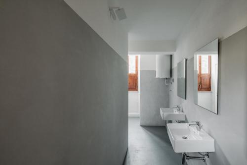 a white bathroom with two sinks and a mirror at OSTELLO HENRY in Buggerru