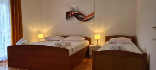 two twin beds in a room with two lamps at Apartments Orlić in Sali