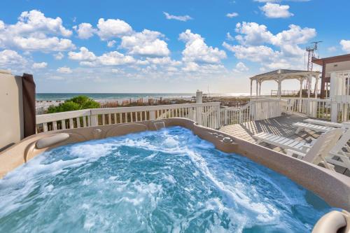 a hot tub on a balcony with chairs and the beach at Sandy Feet Retreat in Panama City Beach