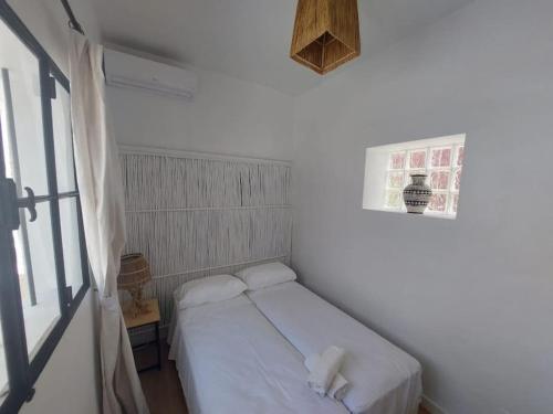 a small white room with a bed and a window at Dar Zwina, Charming and lovely house in Tangier