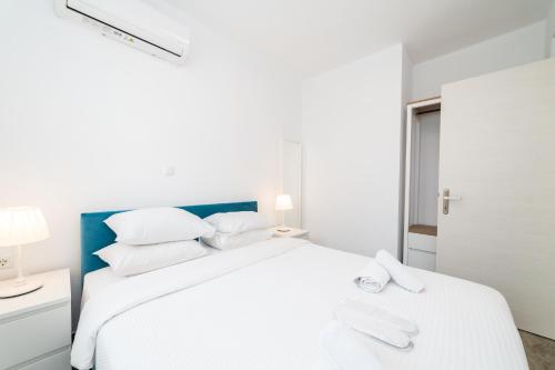 a white bedroom with a large bed with white pillows at Nefeli & Nefeli Luxury Residential Complexes in Ofrínion