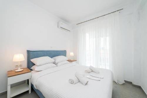 Un dormitorio blanco con una cama blanca con toallas. en Nefeli Residential Complex, en Ofrinion