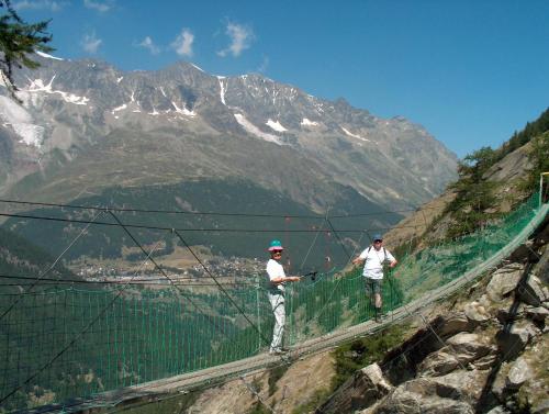 two men on a suspension bridge in the mountains at Wellness- und Schneesporthotel Christiania in Saas-Almagell
