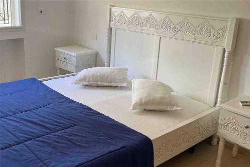 uma cama branca com lençóis e almofadas azuis em Le turc (ennasr) em Ariana
