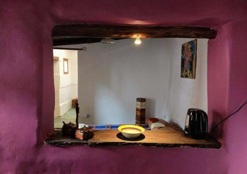 Zimmer mit einer lila Wand mit einem Tisch und einem Spiegel in der Unterkunft Familia Albahaca in Tilcara