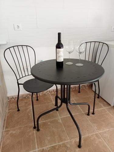 a black table with two chairs and a bottle of wine at Estúdio privado 30 km Lisboa in Gradil