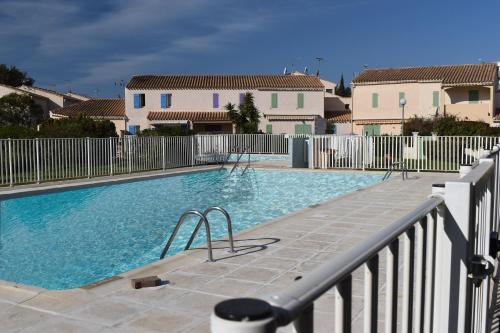 une grande piscine avec une clôture blanche dans l'établissement 4 personnes au Village de la mer, à La Londe-les-Maures