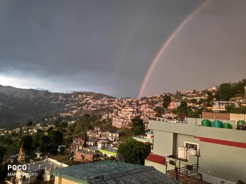 a rainbow in the sky over a city at MangalMurti Himalyan Hotel in Almora