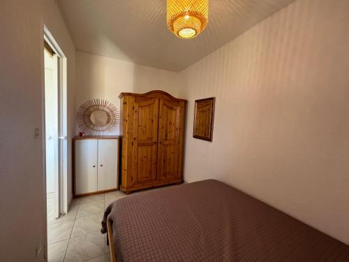 une chambre avec un lit et une armoire en bois dans l'établissement 4 personnes au Village de la mer, à La Londe-les-Maures