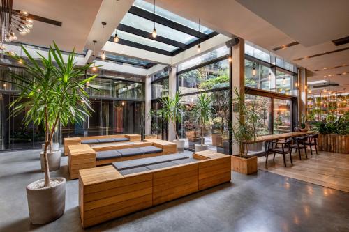 a lobby with tables and potted plants and windows at IOTA Hotel Tbilisi in Tbilisi City