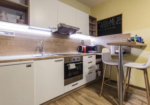 a kitchen with white cabinets and a counter with a table at FLEXIHOME SK - Trieda SNP - private parking spot in Košice