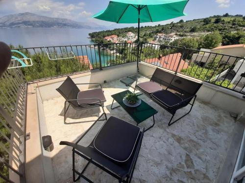 a balcony with chairs and a table and an umbrella at Villa SARA in Postira