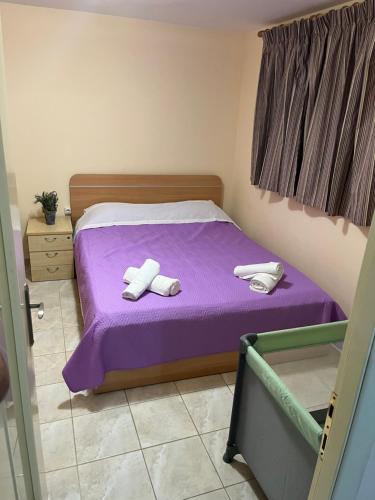 a bedroom with a purple bed with towels on it at billys apartment in Nea Peramos