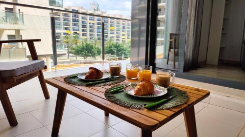 une table avec deux assiettes de nourriture et des verres de jus d'orange dans l'établissement CALA ALTA sun&beach apartaments, à La Cala de Finestra