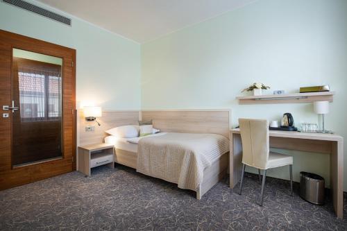 a bedroom with a bed and a desk and a chair at Hotel Mlynska in Uherské Hradiště