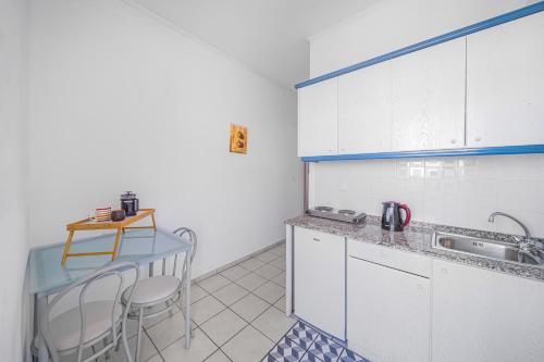 a kitchen with white cabinets and a table and chairs at Happy Days in Malia