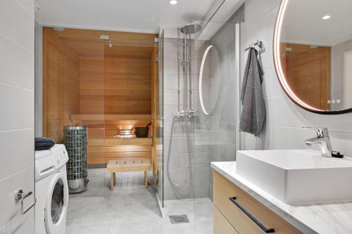 a bathroom with a shower and a sink and a washing machine at HOMELY - Executive Suite 72m2 -Sauna in Helsinki