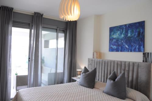 een slaapkamer met een bed met kussens en een kroonluchter bij Apartamento Vanian Gardens Estepona in Estepona