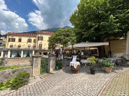 un patio con tavoli e ombrellone di fronte a un edificio di Hotel e Ristorante Cassone a Malcesine