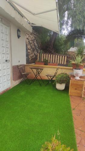 un patio con césped verde, una mesa y un banco en Casita con mirador, en Málaga