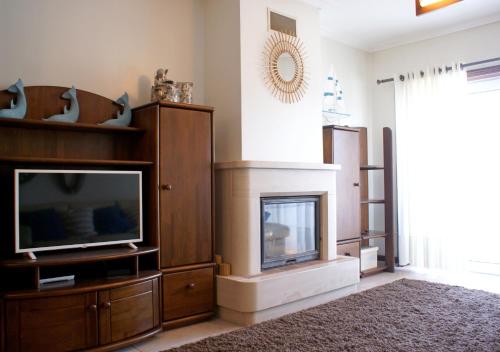 a living room with a television and a fireplace at Barra Azul in Praia da Barra