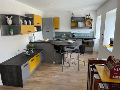 uma cozinha com armários amarelos, uma mesa e cadeiras em Gîte dans un hameau breton - 10 personnes 