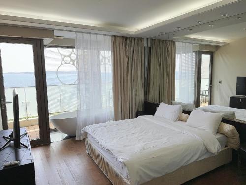 a bedroom with a bed and a bath tub and a window at Seopjikoji Oceanview Apartment in Seogwipo