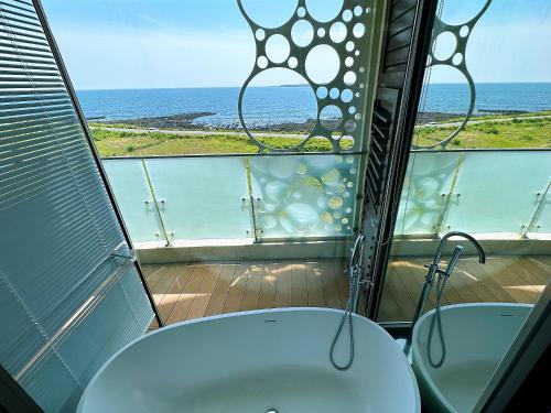 a bathroom with two sinks and a view of the ocean at Seopjikoji Oceanview Apartment in Seogwipo