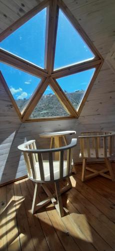 a room with two chairs and a table and a large window at Domos Andinos HostCamp in Potrerillos
