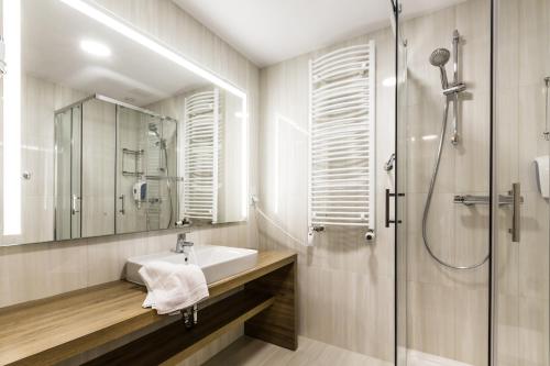 a bathroom with a sink and a shower at Sanatorium Uzdrowiskowe Augustów in Augustów