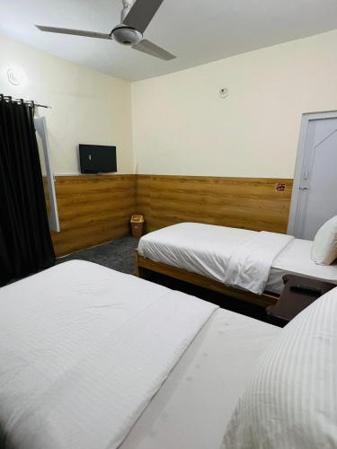 a hotel room with two beds and a flat screen tv at ISLE OF HIGHLAND TOURS Guest House in Gilgit