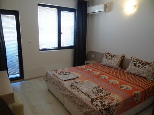 a bedroom with a bed and two windows at Oasis Beach Home Four in Lozenets