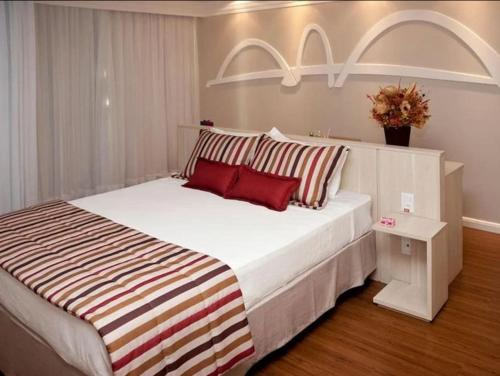 a bedroom with a large white bed with red pillows at Flat Mercure 1km do Planalto Central h07 in Brasilia