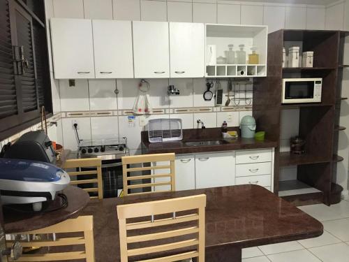 eine Küche mit weißen Schränken sowie einem Tisch und Stühlen in der Unterkunft Excelente casa 300m2 em Bairro Nobre perto de tudo in Natal