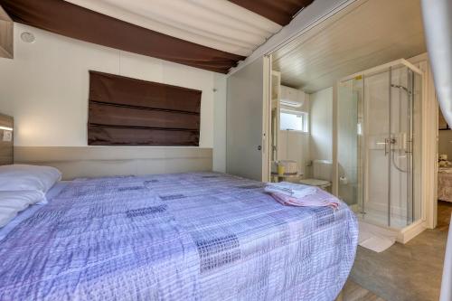 a bedroom with a large bed and a shower at Camping Eden Glamping in Dormelletto