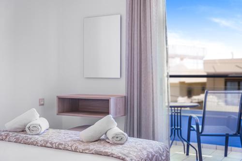a room with two beds and a table and a window at Happy Days in Malia
