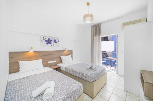 a hotel room with two beds and a balcony at Happy Days in Malia