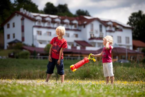 ロイパースドルフ・バイ・フュルステンフェルトにあるFamilien Hotel Krainzの二人の若者がボールとコウモリで遊んでいる