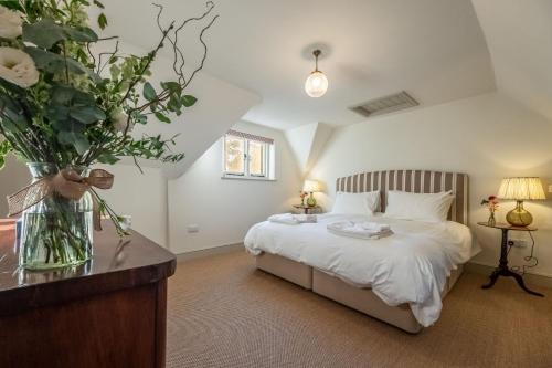 a bedroom with a bed with a vase of flowers at Hensill Farmhouse in Hawkhurst