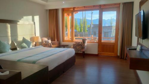a hotel room with a bed and a large window at Lha-Zes in Leh