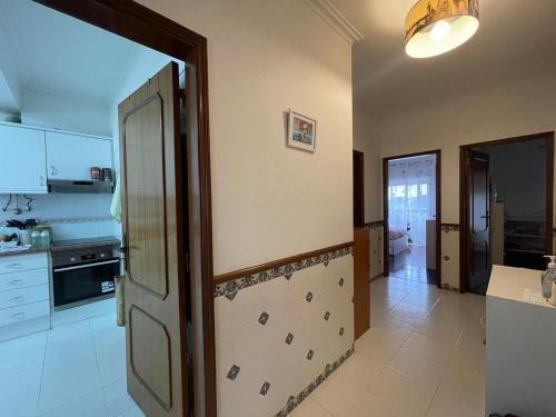 een keuken met een deur naar een keuken met witte apparatuur bij Room THAYS KHAYS in Seixal