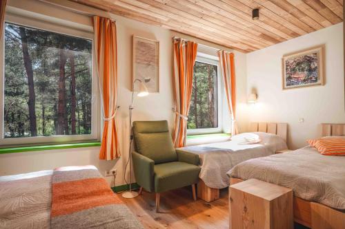 a bedroom with two beds and a chair and windows at Gintarautojai in Palanga