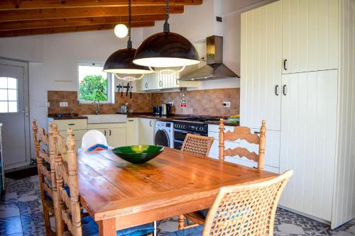 uma cozinha com uma mesa de madeira e cadeiras em Casinhas da Figueira em Budens