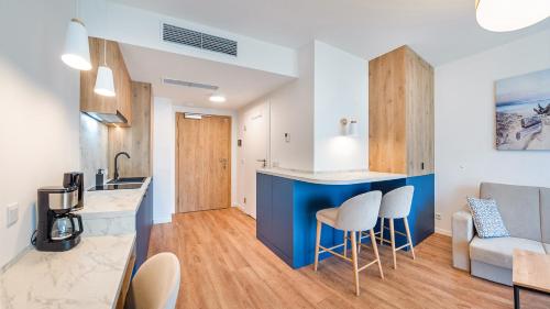 a kitchen and living room with a blue counter and stools at Apartamenty Magnet Jantaris in Mielno
