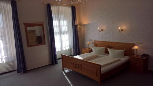 a bedroom with a large bed and two windows at CAREA Hotel Fürstenhof in Haigerloch