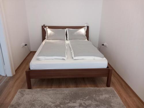 1 cama con sábanas blancas y almohadas en una habitación en Korvin One Apartman, en Pápa