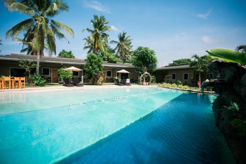 a swimming pool with blue water in front of a house at Hidden Lagoon Resort in Panglao
