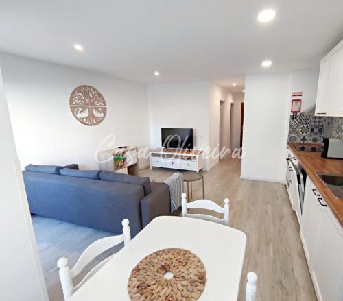 a living room with a blue couch and a kitchen at Casa Oliveira - Sunny 2-Bed Retreat Steps from the Beach in Armação de Pêra
