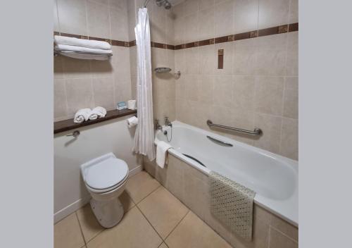 uma casa de banho com um WC, uma banheira e um lavatório. em Allingham Arms Hotel em Bundoran